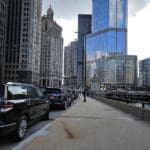 Urban street scene with parked cars and tall modern buildings.